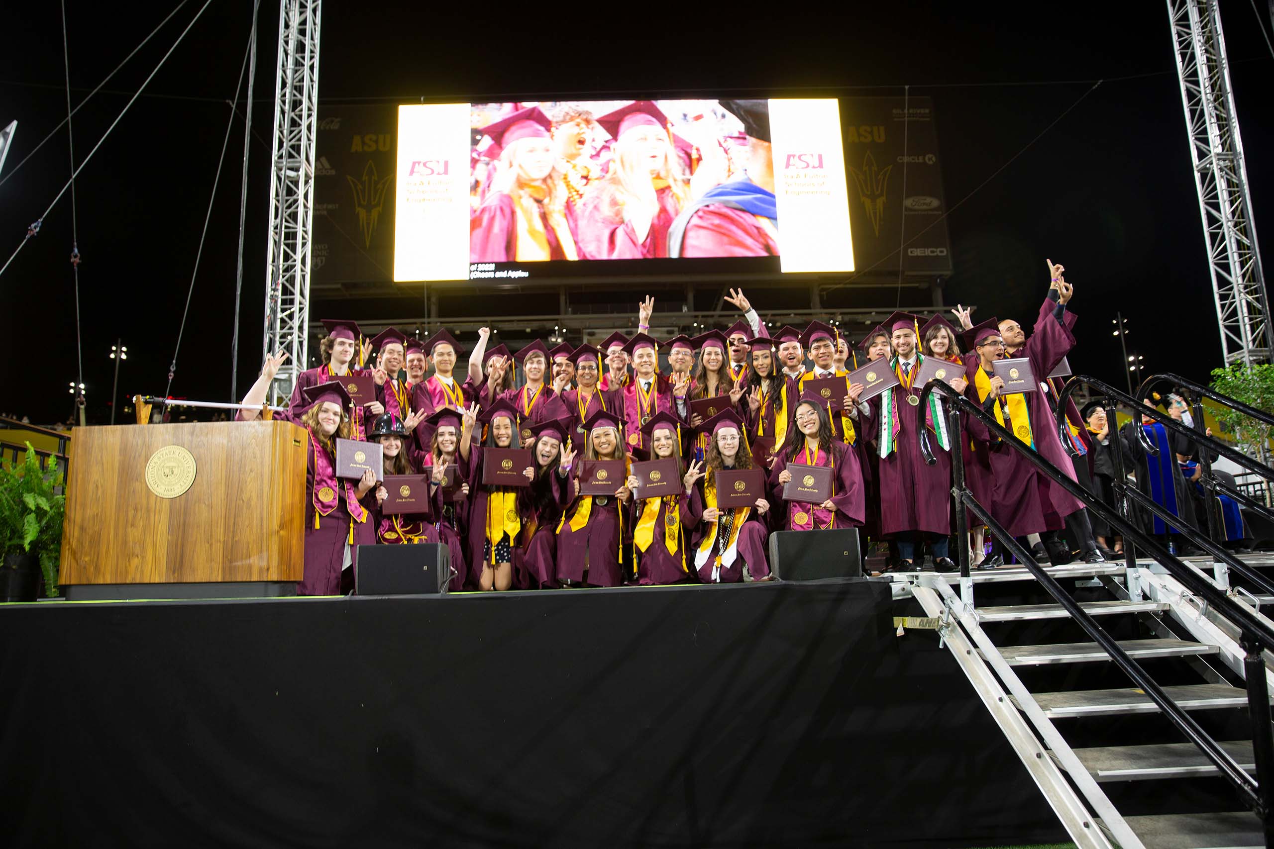 Students gather on stage in their caps and gowns.